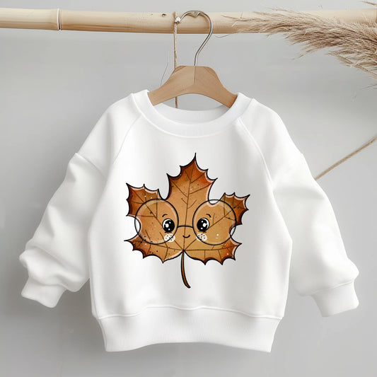 „Kinder-Sweater mit mittig platziertem braunen Ahornblatt-Bügelbild mit Brille; zeigt Größe und Position des Motivs deutlich auf dem Kleidungsstück.“