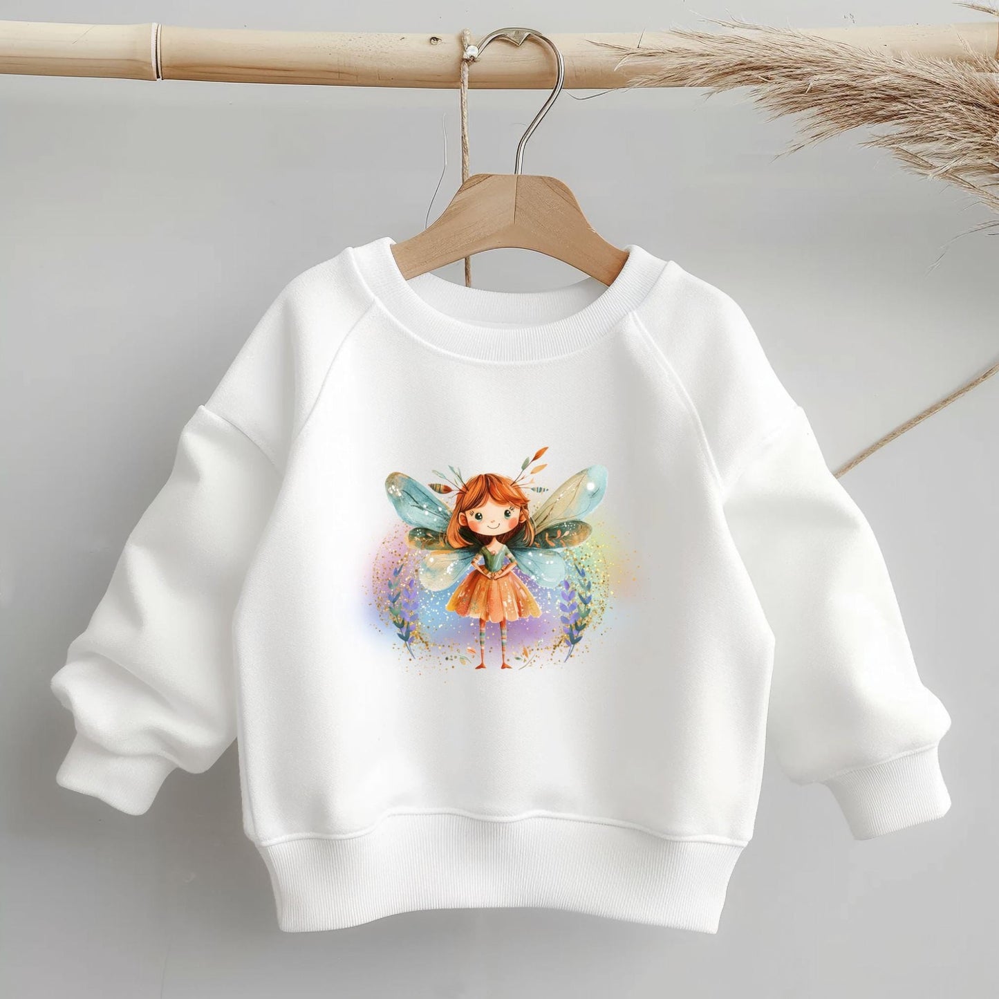 Bügelbild Fee mit buntem Feen-Motiv für Kinderkleidung auf weißem Pullover.