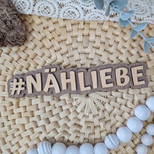 Dekorativer Holzschriftzug #NÄHLIEBE auf geflochtener Unterlage mit DIY-Deko – ideal für Flatlays von Nähprojekten und handgemachten Produkten.