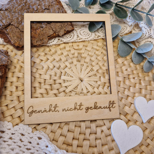 Polaroidrahmen aus Holz mit der Gravur „Genäht, nicht gekauft“ für DIY-Projekte.