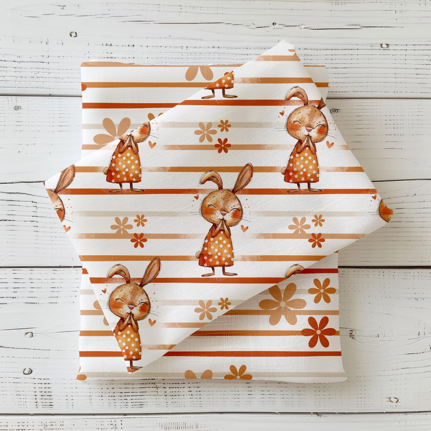 Kinderstoff "Hasenliebe" mit süßen Häschen in gepunkteten Kleidchen auf einem weiß-orange gestreiften Hintergrund mit kleinen Blümchen.