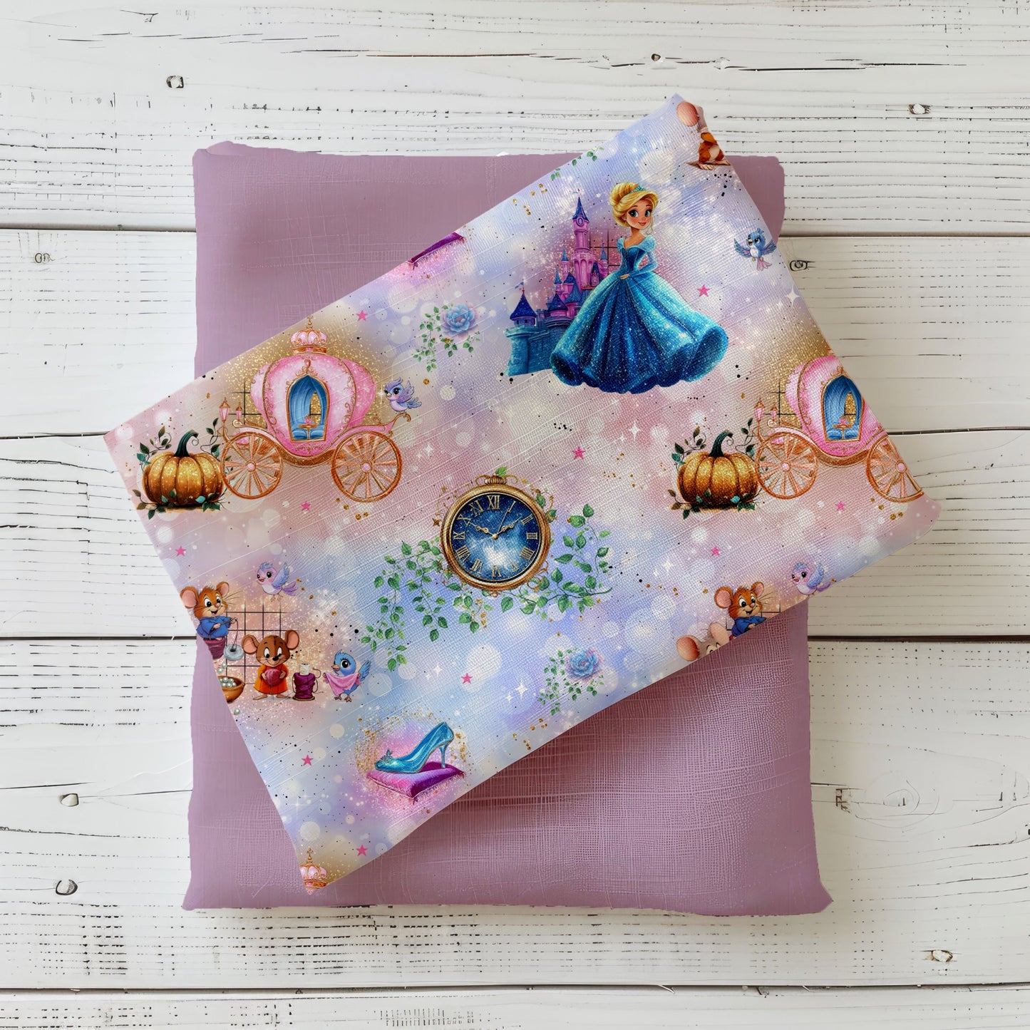 Mockup: Stoff „Prinzessin der Mitternacht“ mit Prinzessin im blauen Kleid, Kutsche, Uhr, Glasschuh und Schloss auf funkelndem Pastellhintergrund; Stoff liegt diagonal auf Uni-Kombistoff, fotografiert auf weißer Holzfläche.