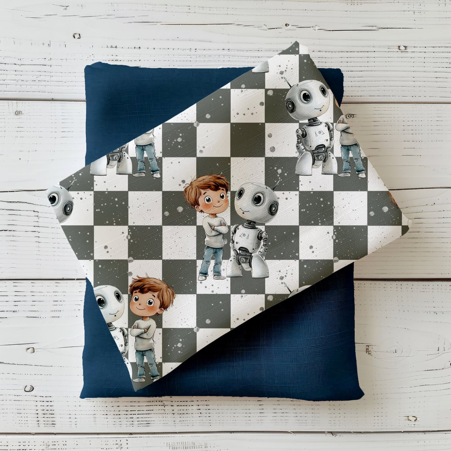 Mockup: Stoff „Roboter-Junge“ mit Junge und weißem Mini-Roboter auf grau-weißem Schachbrett-Hintergrund, feine Sprenkel; Stoff liegt diagonal auf passendem Uni-Kombistoff auf weißer Holzfläche.