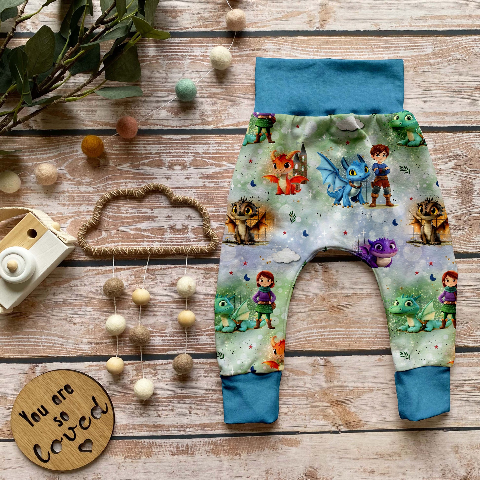 Handgemachte Pumphose „Die Drachenwächter – Azurblau“ mit Ritter- und Drachenmotiv auf French Terry, kombiniert mit azurblauen Bündchen.