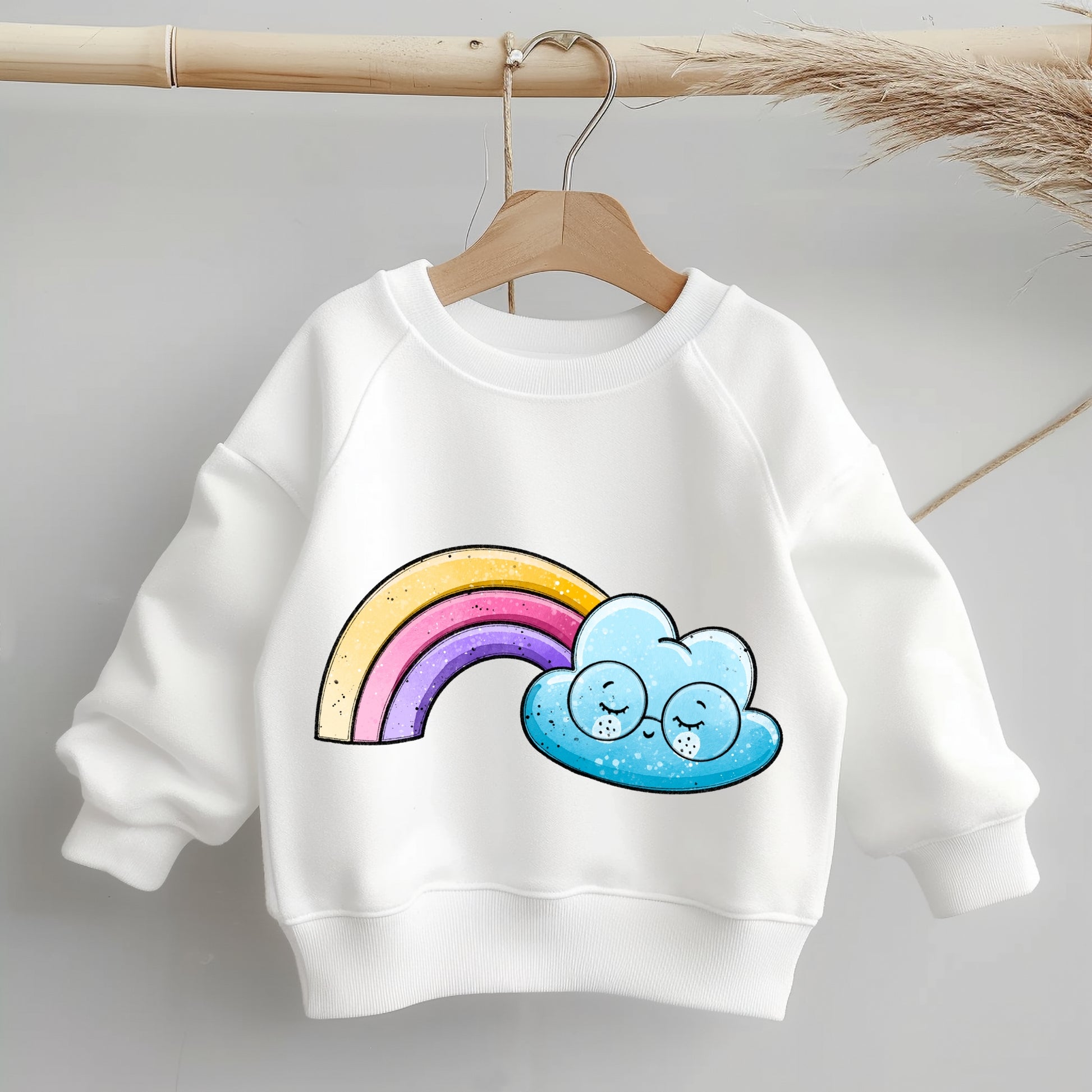 „Mockup eines Kinder-Sweaters: mittig auf der Brust das Motiv ‚Regenbogenwölkchen‘ – blaue Wolke mit Brille neben einem bunten Regenbogen; zeigt Größe und Platzierung des Bügelbilds auf Kleidung.“