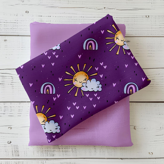 Lila Sonnenstoff Believe in Magic – weicher Jersey mit fröhlicher Sonne, Wolken & Regenbögen.