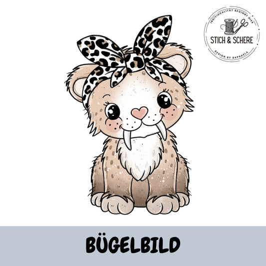 Bügelbild „Säberline der Säbeltiger mit Stirnband“: süßer, sitzender Säbeltiger in Beige/Braun mit Leo-Stirnband, schwarze Konturen; Logo oben rechts; unten grauer Balken mit Schrift „BÜGELBILD“.