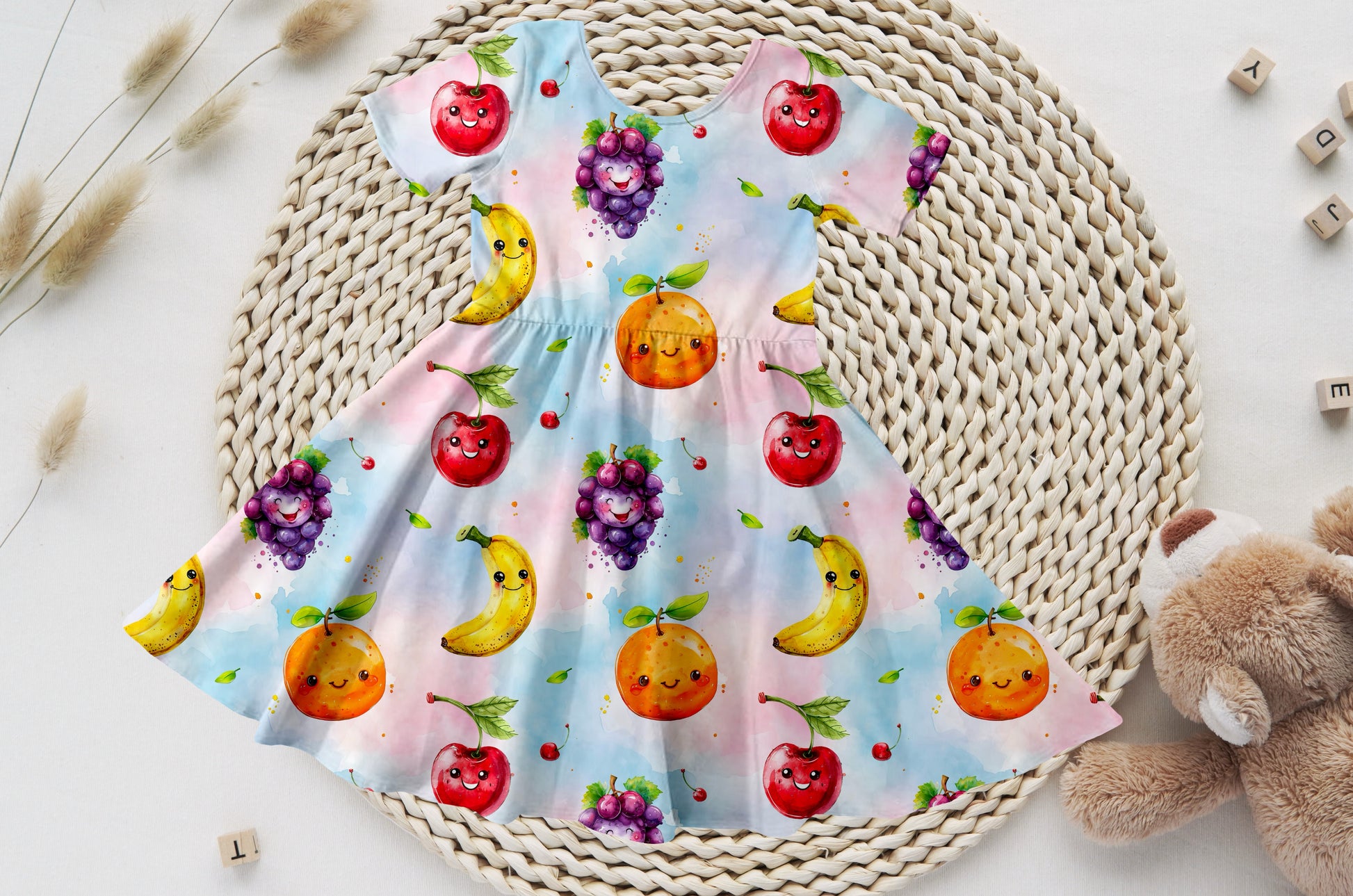 Kinder-Drehkleid mit buntem Obst-Print auf zartem Farbverlauf.
