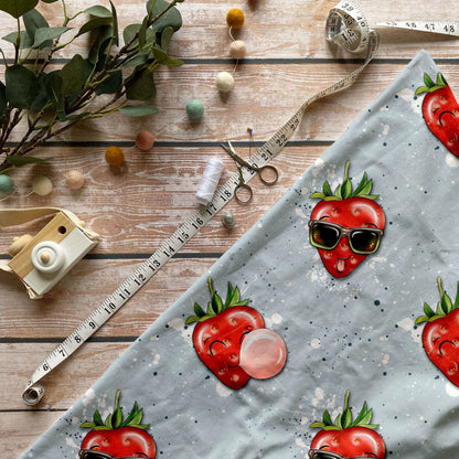 French Terry mit sommerlichem Erdbeer-Print & verspielten weißen Sprenkeln.