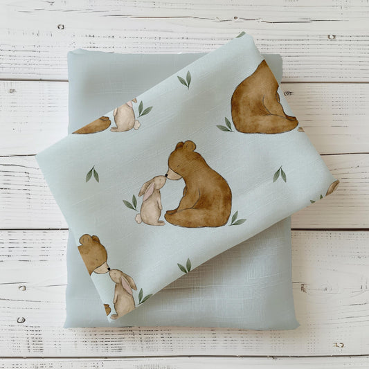 Detailaufnahme des Kinderstoffs "Sanfte Freundschaft" mit Bär und Hase auf pastellblauem Hintergrund.