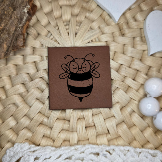 Kunstlederlabel „Buntes Glück“ mit niedlicher Biene, schwarz graviert auf braunem Kunstleder, ca. 4×4 cm