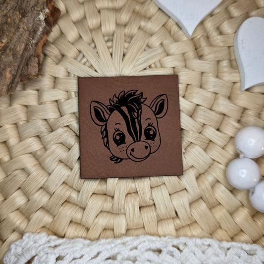 Quadratisches Kunstlederlabel mit graviertem Zebrakopf mit Streifenmuster, Motivdesign von Katzengold-Designs, gefertigt von Stich & Schere