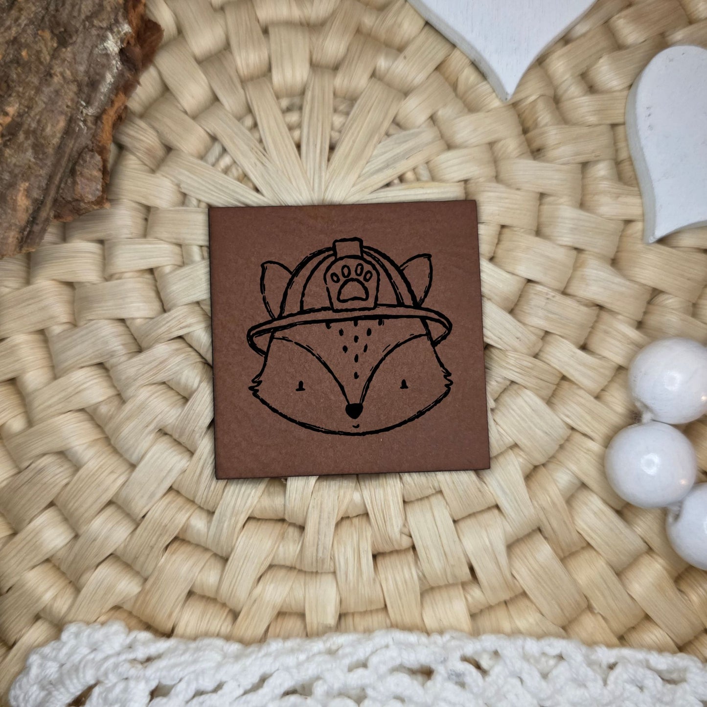 Quadratisches Kunstlederlabel mit graviertem Fuchs mit Feuerwehrhelm und Pfotenabzeichen, Motivdesign von Katzengold-Designs, gefertigt von Stich & Schere