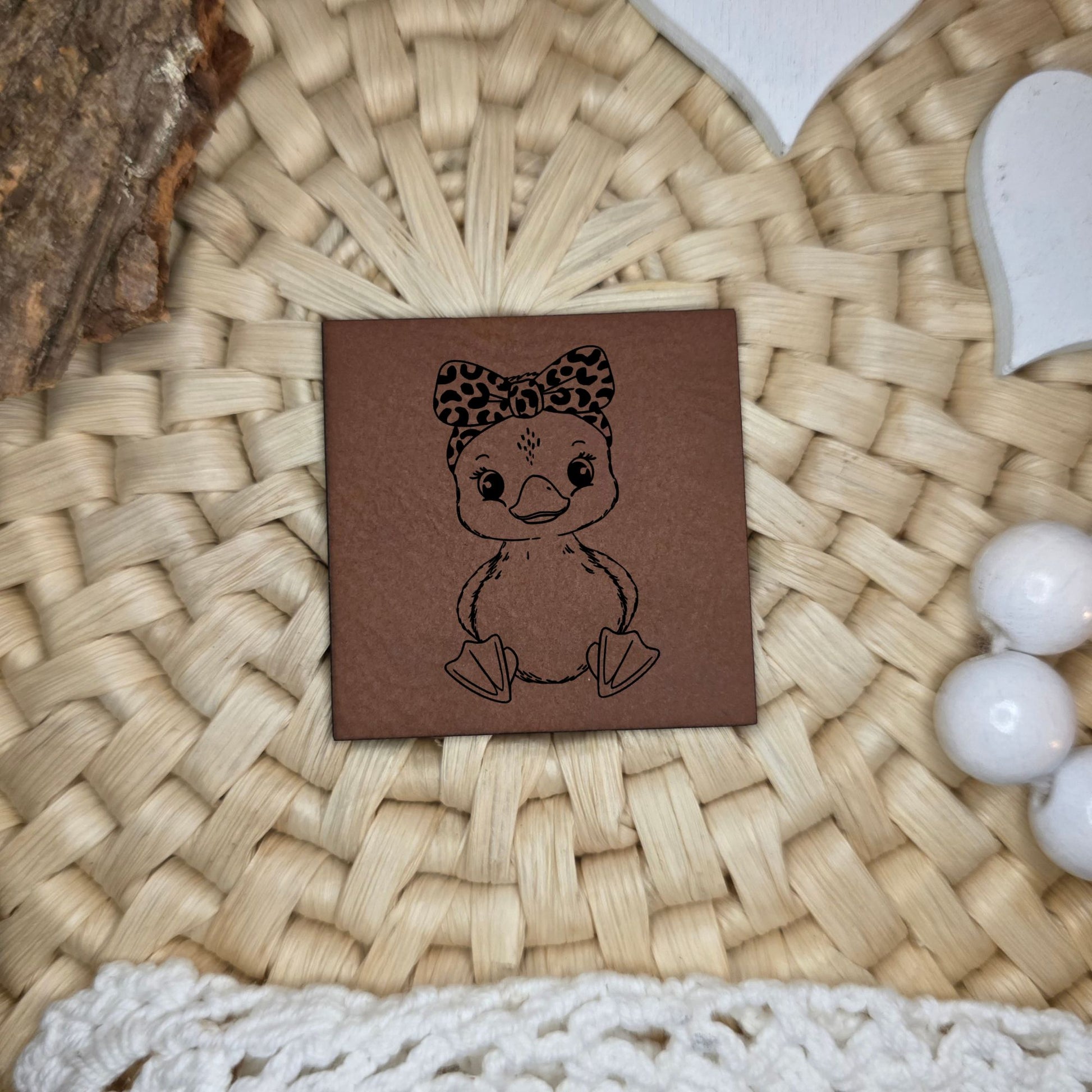 Quadratisches Kunstlederlabel mit graviertem süßem Gänseküken mit Schleife, Motivdesign von Katzengold-Designs, gefertigt von Stich & Schere