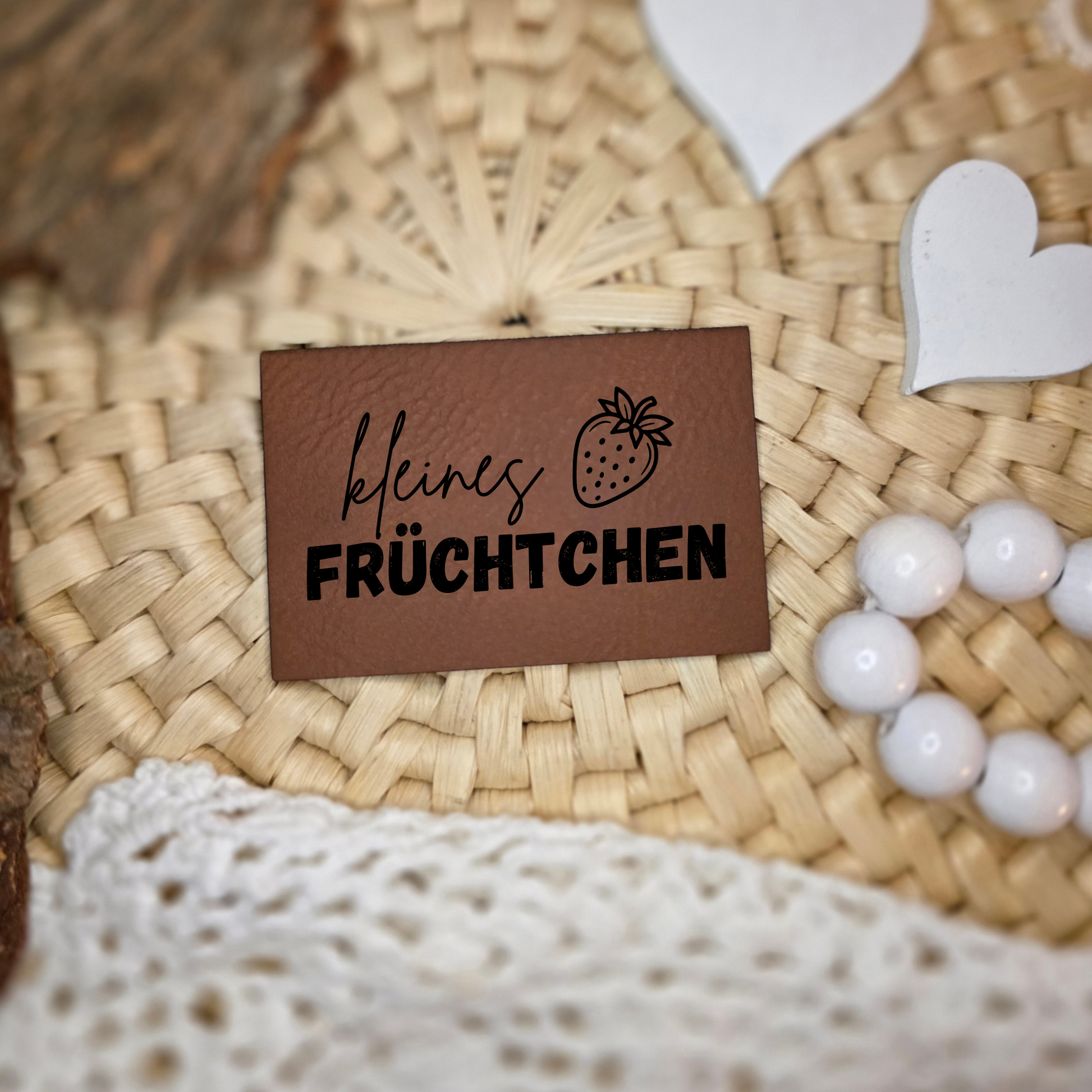 Kunstlederlabel „kleines Früchtchen“ mit Erdbeer-Motiv auf natürlicher Deko fotografiert