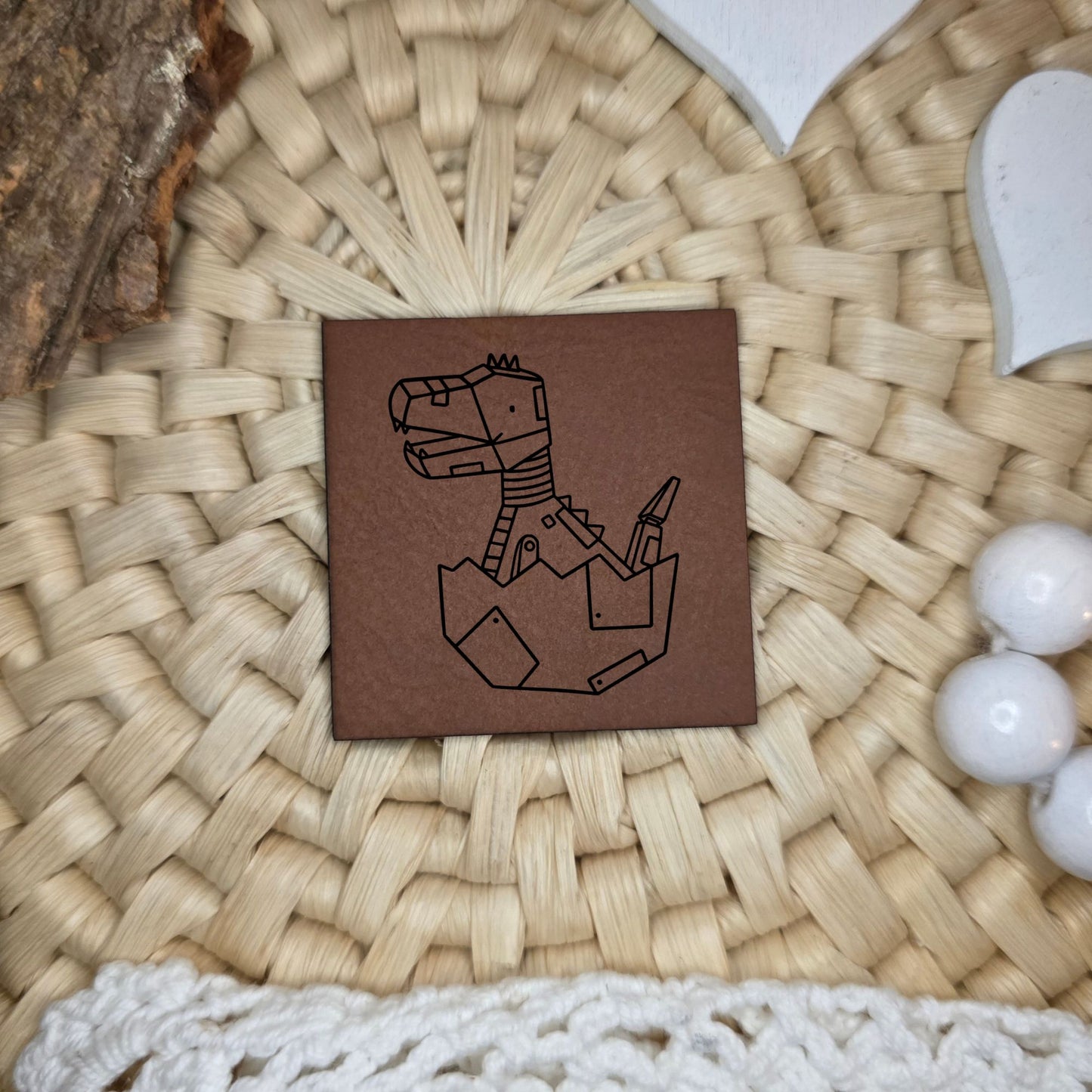 Quadratisches Kunstlederlabel mit graviertem Roboter-Dino, der aus einem Ei schlüpft, Motivdesign von Katzengold-Designs, gefertigt von Stich & Schere