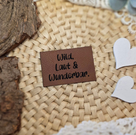 unstlederlabel „Wild, laut & wunderbar.“ auf Bastuntergrund dekoriert