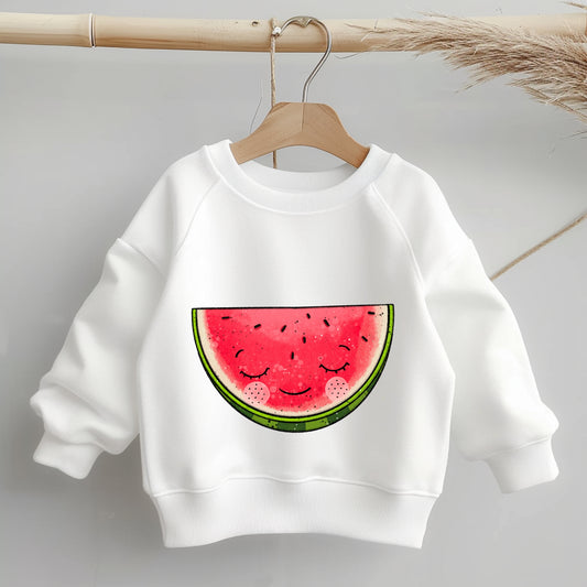 „Mockup eines einfarbigen Kinder-Sweaters: Mittig auf der Brust das Bügelbild einer halben, lächelnden Wassermelone; zeigt Größe und Platzierung des Motivs auf Kleidung.“
