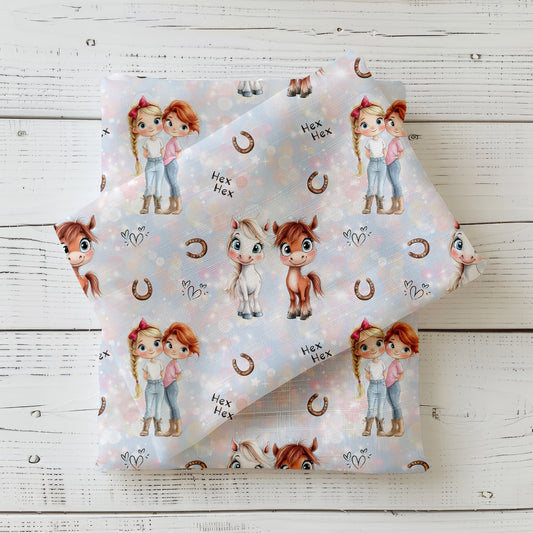 Gefalteter Stoff „Mimi & Mina“ mit süßen Pony- und Mädchenmotiven auf pastellfarbenem Hintergrund.