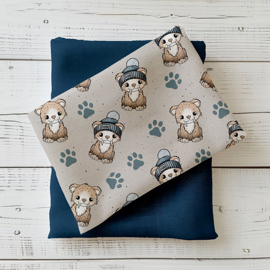 Handgemalter Kinderstoff „Säbi“ – Säbelzahntiger mit Mütze & Pfoten auf sandbeigem Grund, kombiniert mit dunkelblauem Kombistoff (Katzengold-Designs)