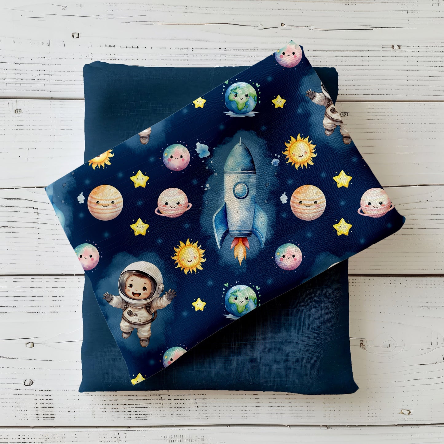 Mockup mit dunkelblauem Astronauten-Stoff: kindlicher Weltraum-Print mit Rakete, Planeten, Sonne, Sternen und kleinem Astronauten – präsentiert auf gefaltetem Uni-Stoff in Dunkelblau, dekoriert auf hellem Holzuntergrund.