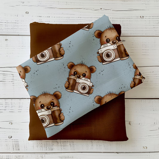 Kinderstoff mit Bärchen und Kamera auf blauem Hintergrund mit kleinen Farbsprenkeln