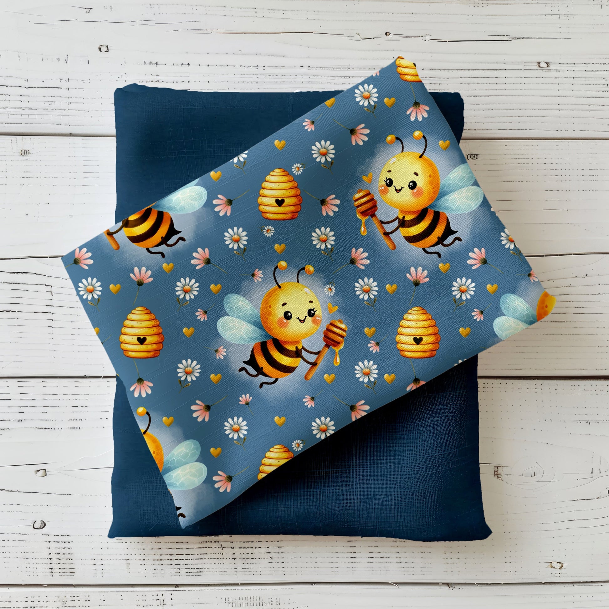 Mockup: Stoff „Bee Happy“ – niedliche Bienen mit Honiglöffel, Bienenkörbe, Gänseblümchen & goldene Herzen auf taubenblauem Hintergrund; Stoffkachel diagonal auf passendem Uni als Kombistoff.