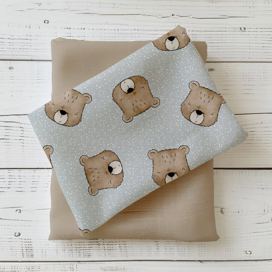 Mockup: Stoff „Benji der Bär“ – Bärenköpfe in Brauntönen auf blaugrauem, weiß gesprenkeltem Hintergrund; Stoffkachel diagonal auf passendem Uni in Taupe als Kombistoff.