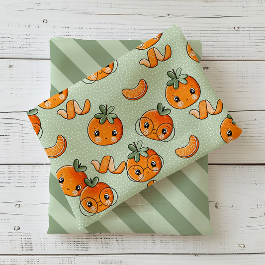 Verspieltes Muster: orange Mandarinen mit Gesichtern, Mandarinen-Spalten und Schalen auf salbeigrünem Polka-Dot-Fond; kindlich gezeichnet.