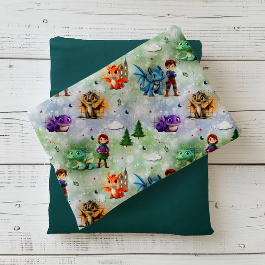 Mockup: Stoff „Die Drachenwächter“ – Kinder mit Drachen (blau, grün, orange, violett), Sterne, Monde, Wolken & Tannen auf grünem Bokeh-Hintergrund; Stoffkachel diagonal auf passendem Uni als Kombistoff.