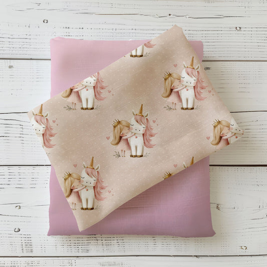 Mockup: Stoff „Einhorn & Prinzessin“ – weißes Einhorn mit rosa Mähne und Prinzessin mit Krone, kleine Herzen auf rosé-beigem Grund; Stoffkachel diagonal auf passendem Uni in Nude/Rosé als Kombi.