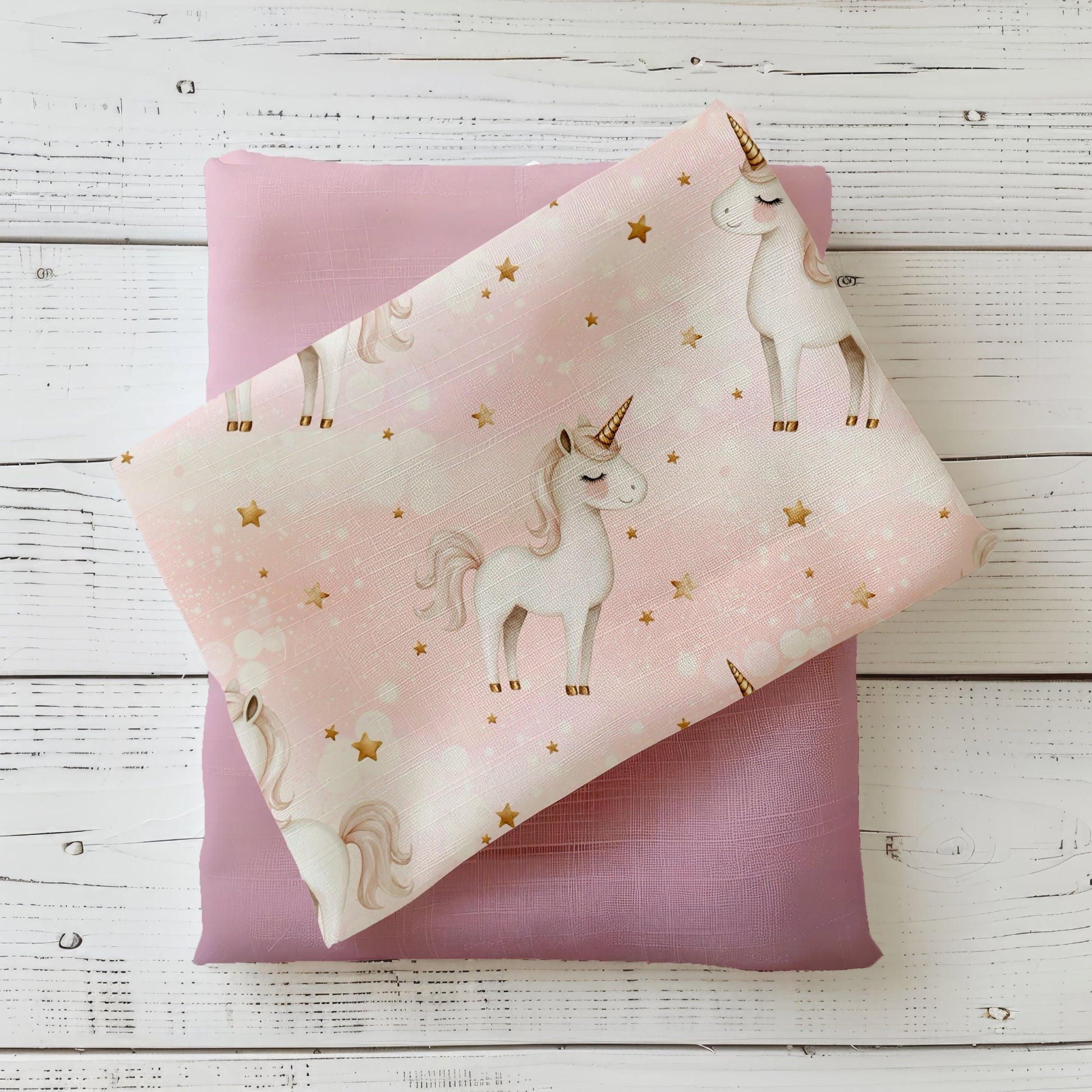 Rosa Stoff mit weißen Einhörnern und goldenen Sternen – Design „Einhornglück“ auf Produktfoto.