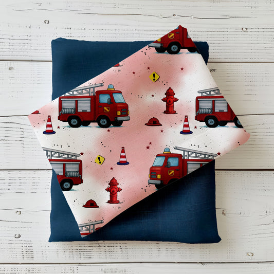 Heller rot-weißer Stoff mit roten Feuerwehrautos, Hydranten und Warnkegeln – Design „Feuerwehr Crew“ auf Produktfoto.