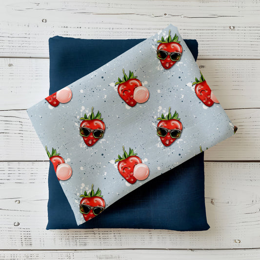 Mockup: Stoff „Freche Erdbeere“ – rote Erdbeeren mit Sonnenbrille und Kaugummi-Blasen auf hellblauem, gesprenkeltem Hintergrund; Stoffkachel diagonal auf passendem Uni in Navy/Dunkelblau als Kombi.