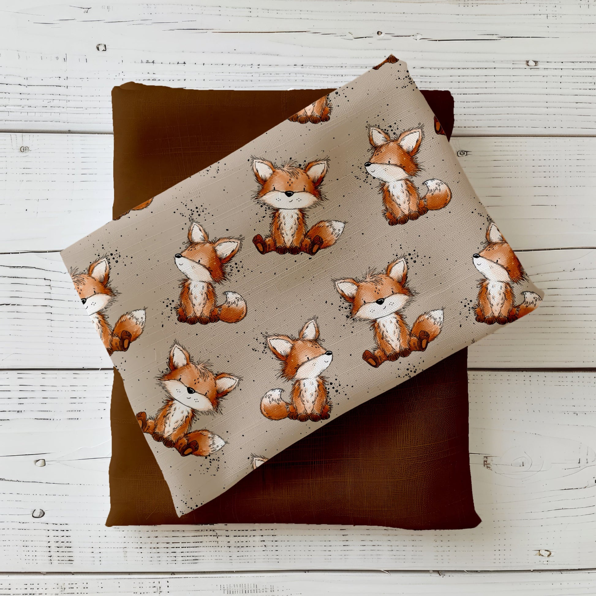 Stoff-Mockup „Fuchstag“ mit niedlichen, handgezeichneten Füchsen auf ruhigem, naturfarbenem Hintergrund, kombiniert mit warmem Uni-Stoff in Braun- und Rosttönen.
