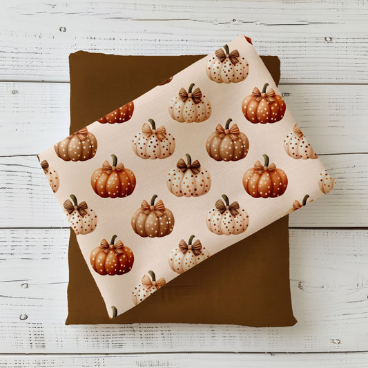 Herbststoff „Gepunktete Kürbisse“ mit Kürbissen in Beige, Creme und Orange, verziert mit Punkten und Schleife.
