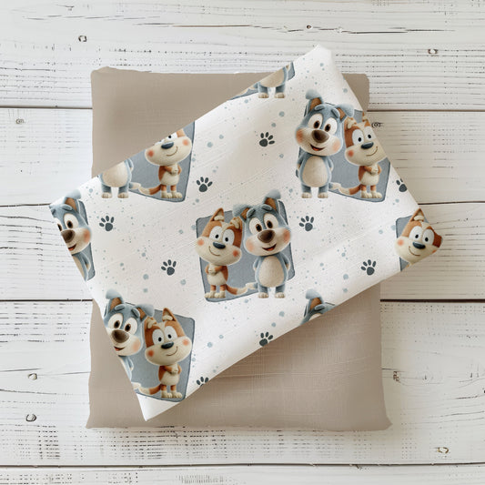 Stoff „Geschwisterhunde“ mit zwei fröhlichen Hunden: einer in Grau, einer in Beige, beide mit großen Augen und rosigen Wangen. Hintergrund mit zarten Farbklecksen und kleinen Pfotenabdrücken.
