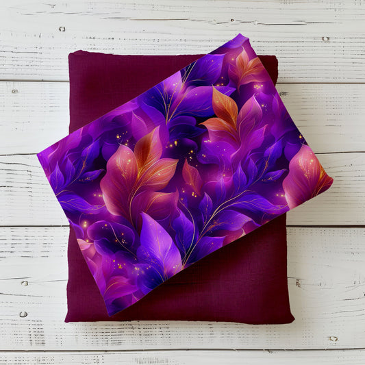 Glowing Flowers Stoff kombiniert mit uni Stoff in Bordeaux. Leuchtende Blüten und Blätter in Lila- und Beerentönen mit eleganten Goldakzenten.