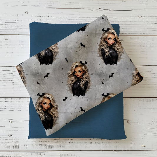 Gefalteter Stoff mit dem Design  "Gothic Glam" in grau – eine Frau mit lockigen blonden Haaren mit Fledermaus im Haar, schwarz gekleidet auf einem grauen Hintergrund in Beton Optik mit Rissen. Kleine schwarze Fledermäuse und weiße herzen befinden sich in den Zwischenräumen.