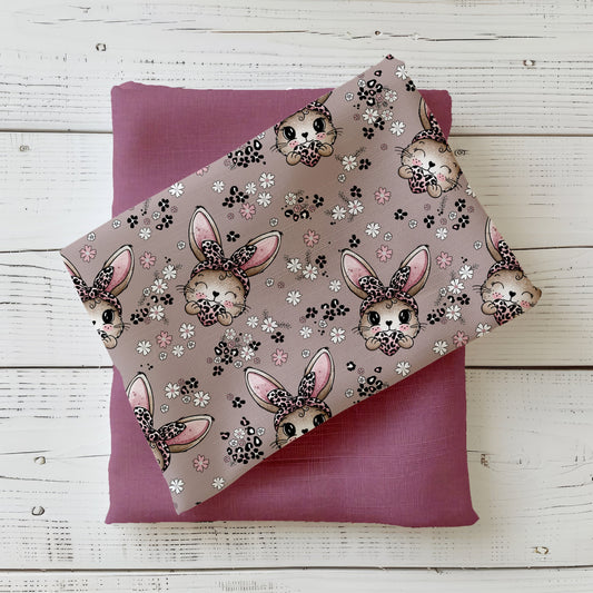 Stoffdesign „Häschen“ mit niedlichen Hasenmotiven, Blumen und Herzchen in warmen Rosé- und Naturtönen, dekorativ gefaltet auf hellem Hintergrund.