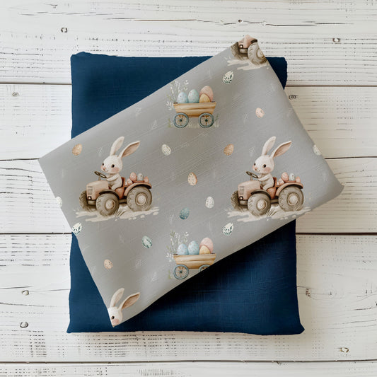 Hasenfahrt Nebelgrau Stoff mit Häschen auf Traktor, Ostereiern und floralen Details auf grauem Hintergrund
