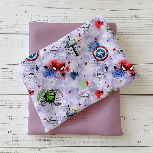 Comic-Stoff mit Superhelden-Motiven – Maske, Schild & Faust auf fliederfarbenem Glitter-Hintergrund.