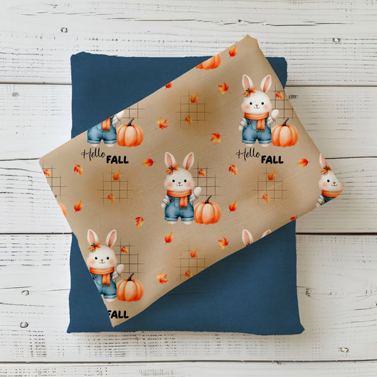 Herbststoff „Herbsthäschen – Hello Fall“ mit Hase, Kürbis, fallenden Blättern und Schriftzug auf beigem Hintergrund.