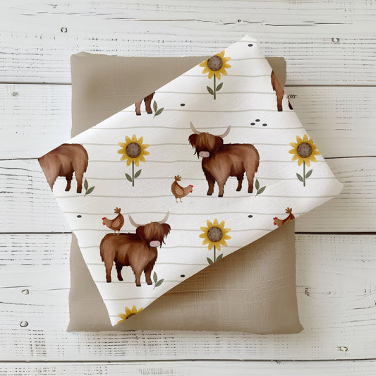 Mockup: Stoff „Hochlandrind & Huhn“ – Highland Cows, Hühner & Sonnenblumen auf weißem, fein linierten Hintergrund; Stoffkachel diagonal auf passendem Uni als Kombi.