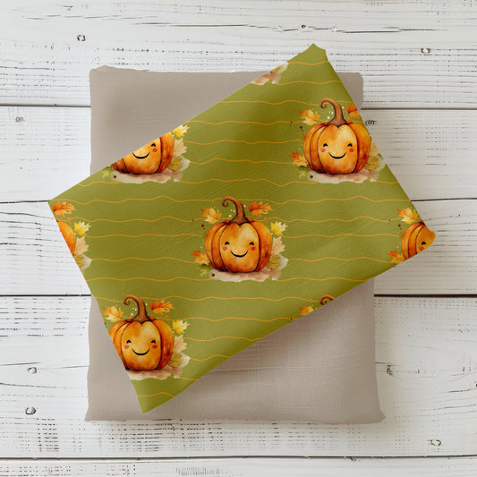 Herbststoff „Kleiner Kürbis“ mit lächelndem Kürbis und bunten Herbstblättern auf olivgrünem Hintergrund.