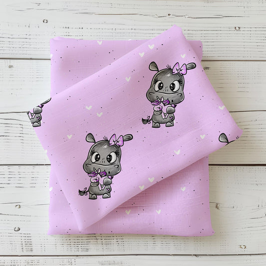 „Kinderstoff Kleines Nilpferd von Schnubbirella – gefalteter Stoff mit Nilpferd, Kuscheltier, Herzen & Sprenkeln in Flieder auf passendem Untergrund, als Mockup präsentiert.“