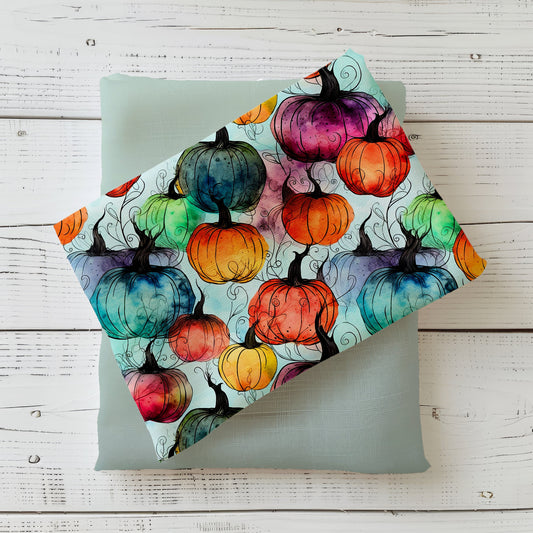Bunter Herbststoff „Kürbisse“ mit Aquarell-Kürbissen in Orange, Blau, Grün, Gelb und Lila auf hellem Hintergrund.