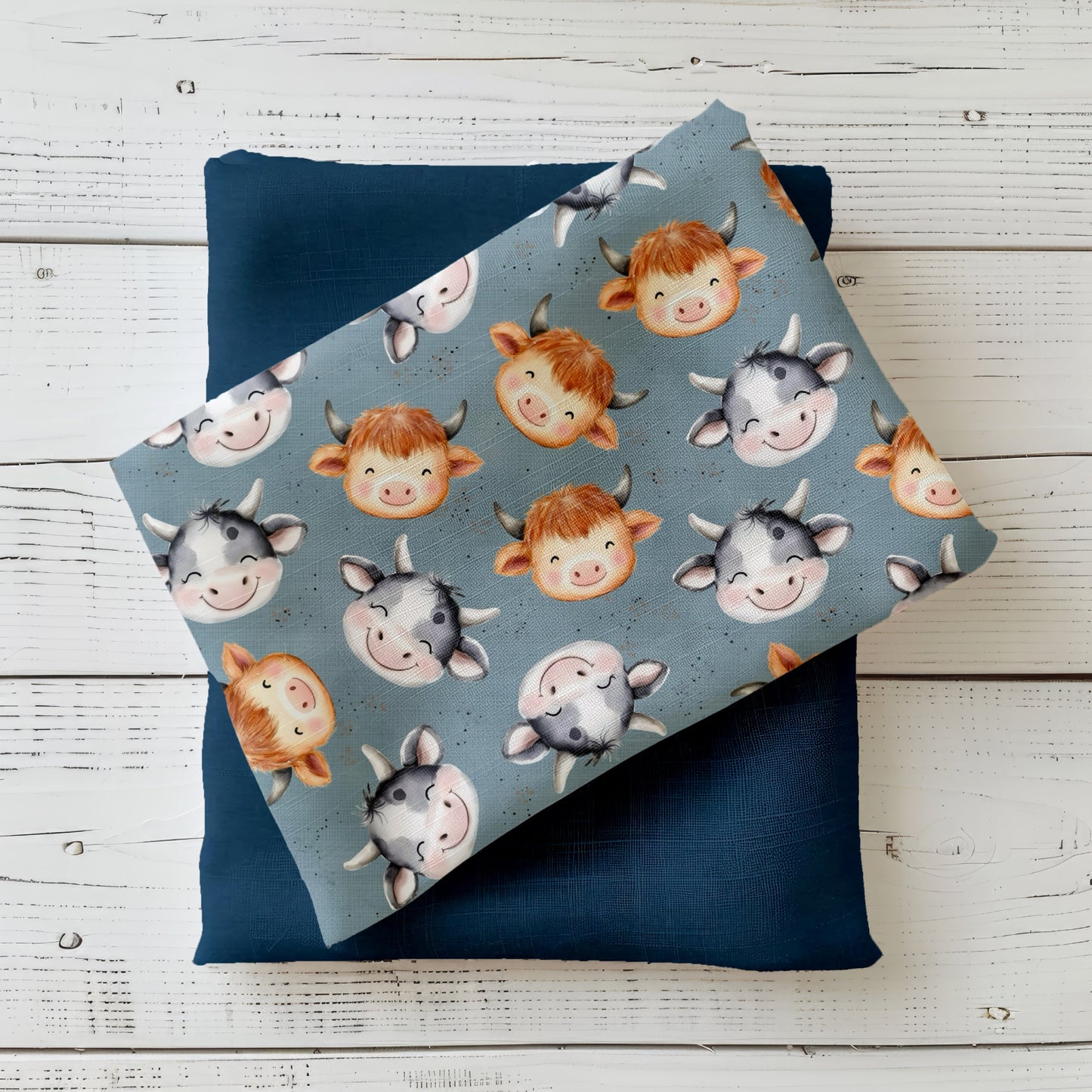 Blaugrauer Stoff mit niedlichen Kuhgesichtern in verschiedenen Farben – Design „Kuhkumpels“ als Produktfoto.