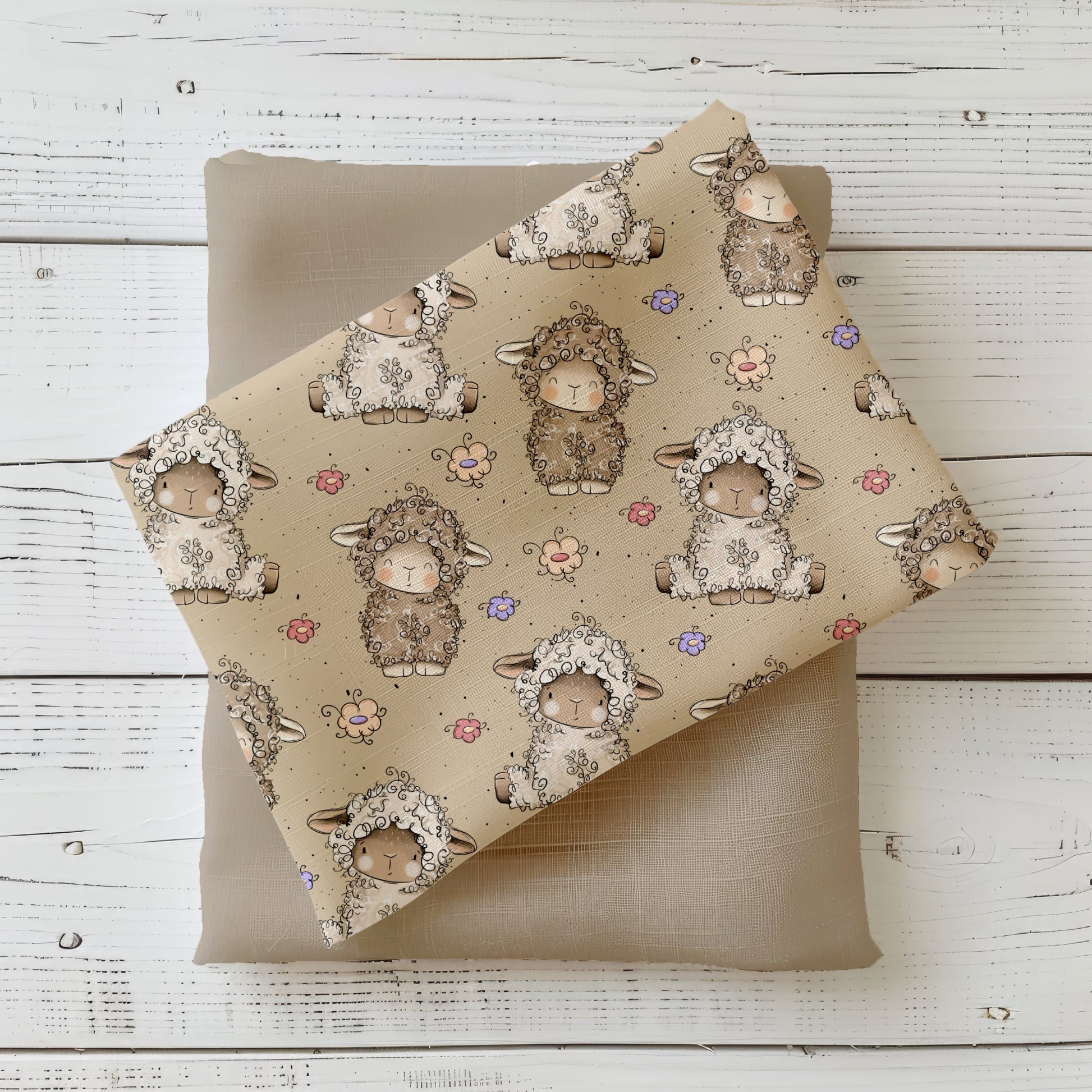 Stoff-Mockup mit dem Design „Lämmchen“: beigegrundiger Stoff mit liebevoll illustrierten kleinen Lämmchen, zarten Blümchen und feinen Sprenkeln. Der Stoff ist locker gefaltet arrangiert und mit einem passenden Uni-Stoff in Naturtönen kombiniert, um Farbwirkung, Motivgröße und Kombinierbarkeit der Meterware realistisch darzustellen. Design von Katzengold-Designs.