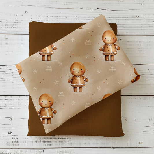 Weihnachtsstoff „Lebkuchenmann“ mit süßem Lebkuchenmännchen, Schneeflocken und Geschenken auf beigem Hintergrund.